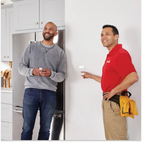 Ace Hardware Home Services electrician flipping a light switch while talking with a homeowner